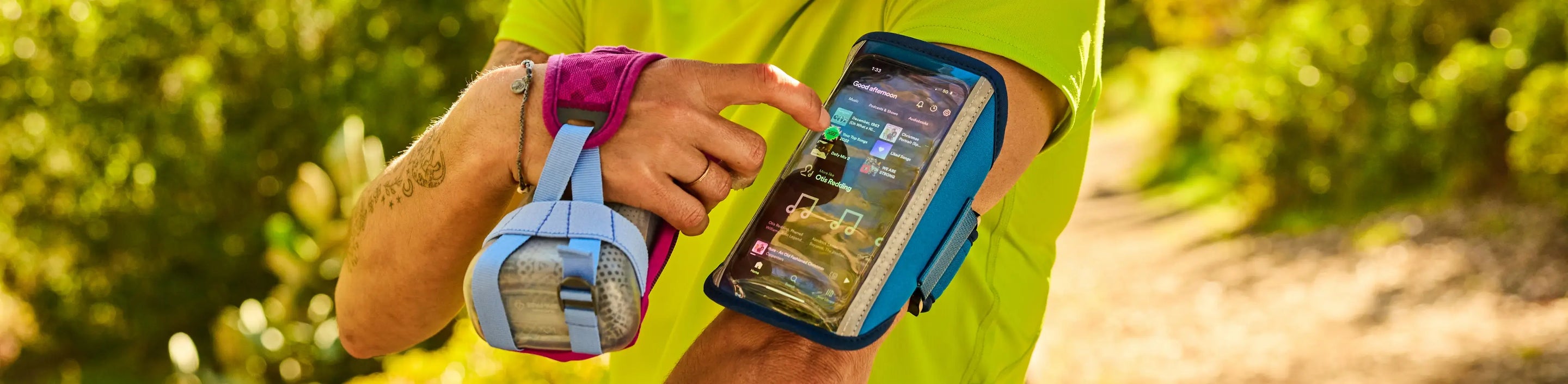 runner with handheld bottle in one hand and a Nathan Sports arm band holding cell phone